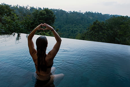 woman raising her hands and forming heart on body of water thumbnail