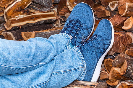 person in blue low-top sneakers leaning on fire woods thumbnail