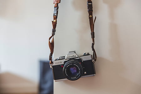 black and gray camera hanging on white wall thumbnail