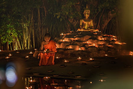 man wearing monk suit behind Gautama statue during nighttime thumbnail