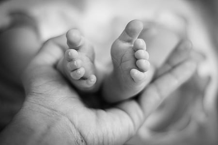 grayscale photo of person holding baby's feet thumbnail