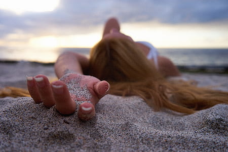 shallow photography of woman holding sand during daytime thumbnail