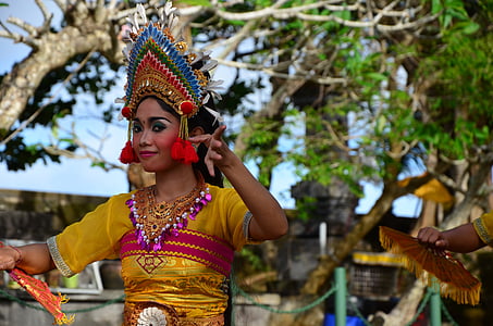 woman wearing yellow and pink traditional dress dancing under brown tree thumbnail