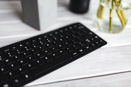 Black keyboard with pencils on a white table thumbnail