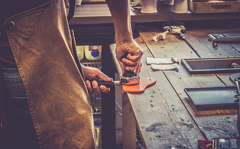 person pressing gray and black metal tool on wooden table thumbnail