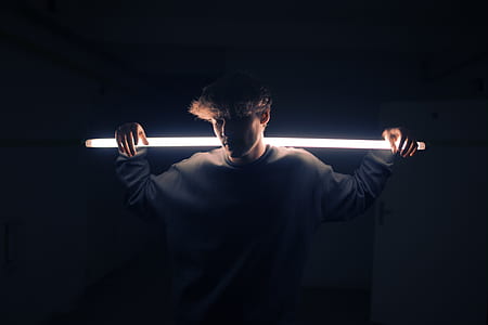 man in gray sweater holding light fluorescent light thumbnail