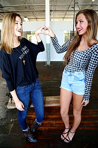 two smiling women making heart handsigns thumbnail