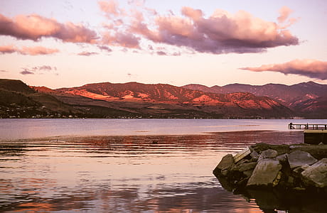 Sunset clouds over lake and red mountains thumbnail