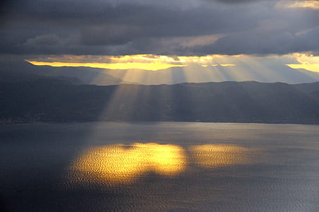 sun rays on body of water during dark clouds thumbnail