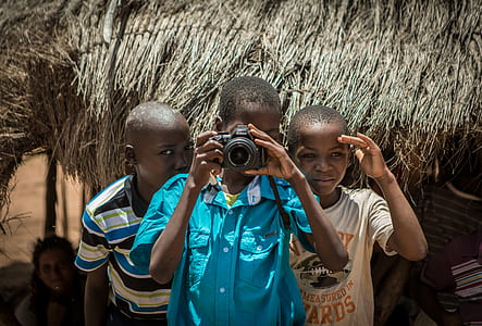 man taking picture using DSLR camera together with his two male friends during day thumbnail