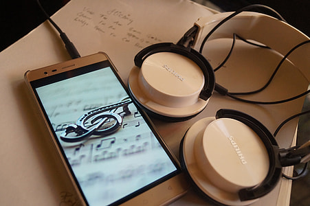 white Philips headphones beside smartphone thumbnail