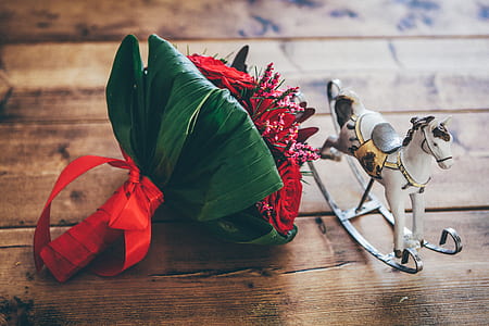 red and green flowers beside horse figurine on wooden surface thumbnail