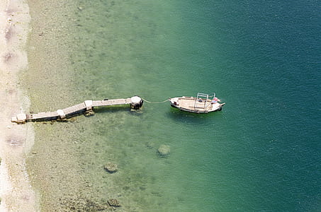 high-angle photo of gray dock beside white boat on body of water thumbnail