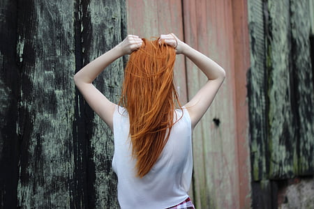 woman standing while holding her hair near wall thumbnail
