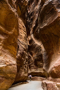 person walking between brown caves at daytime thumbnail