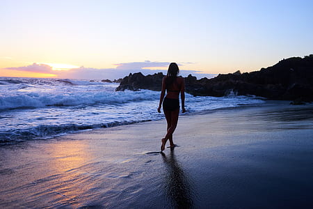 silhouette of woman walking on seaside at golden hour thumbnail