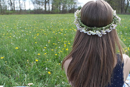 person in blue sleeveless top sitting in green grass lawn wearing floral headband during daytime thumbnail