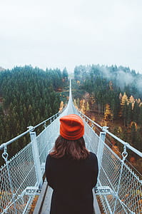 woman wearing orange beanie white standing on black steel bridge thumbnail