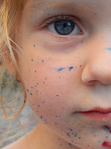 blue splatter paint on toddlers face thumbnail