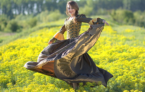 woman wearing yellow and gray dress standing on the middle of yellow field of flowers thumbnail