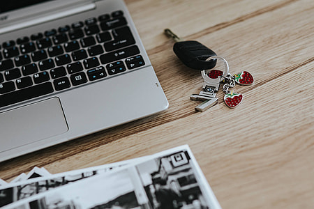 Black-and-white photos with a silver laptop, a smartphone, car keys, pencils and a camera thumbnail