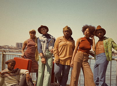 people posing for photo leaning against white handrail near body of water during daytime thumbnail
