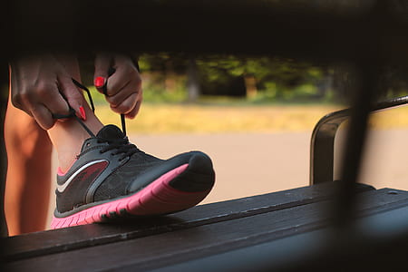 Woman in Black and Pink Sneaker Tying Lace of Her Shoe thumbnail
