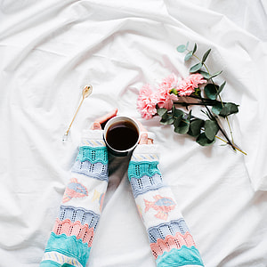 person holding teacup beside pink petal flower thumbnail