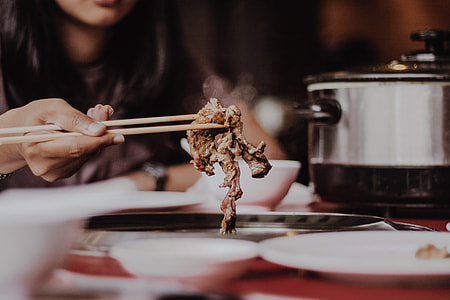 person holding chopsticks while picking up a cooked meat thumbnail