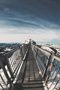 gray metal bridge across snow covered mountains thumbnail
