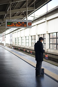 man standing beside train railing thumbnail