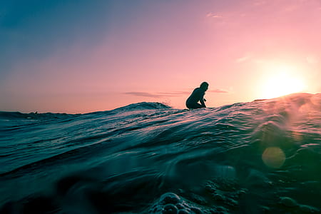 person sitting on gray mountain at golden hour thumbnail