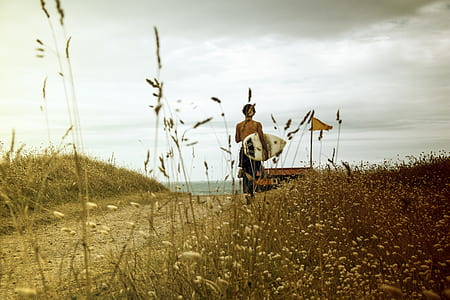 man carrying white surfboard during daytime thumbnail