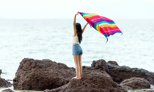 Girl standing on a rock with blanket on the seashore in the Maldives thumbnail
