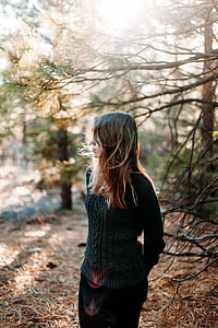 woman in green sweater standing in forest during daytime thumbnail