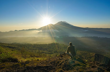 man sitting on mountain cliff looking at sunrise thumbnail