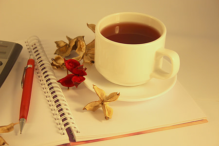 white ceramic teacup and saucer on notebook with flowers thumbnail