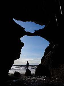 silhouette of man standing in rock near body of water thumbnail