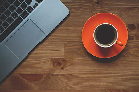 cup of coffee beside gray laptop on brown wooden desk thumbnail