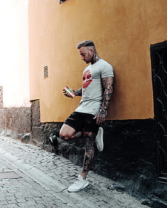 man holding can leaning against wall thumbnail