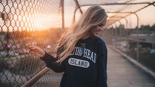 photography of woman holding chain link fence during sunset thumbnail