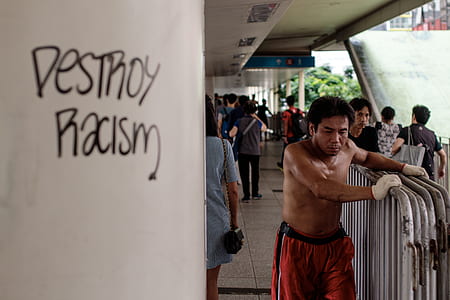 topless man wearing red bottoms holding gray barricades thumbnail