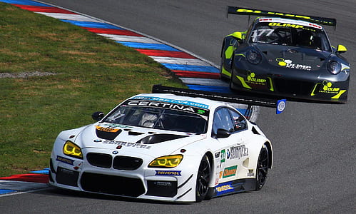 white BMW racing car and gray sports coupe behind on racing track thumbnail