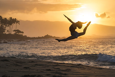 woman doing acrobats near shoreline during golden hour thumbnail