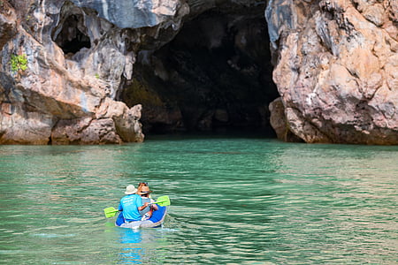 person riding raft holding oar over calm body of water near cave thumbnail
