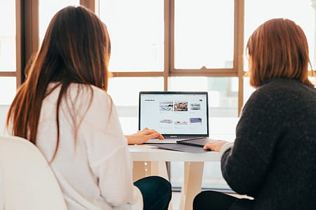 two women facing laptop computer thumbnail