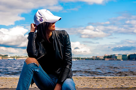 woman sitting on concrete pavement over body of water during daytime thumbnail