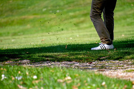 person wearing white shoes standing on green grass field thumbnail