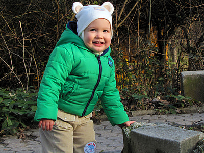 boy wearing bubble jacket standing in front of plants thumbnail