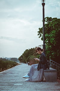 woman wearing black leather jacket sitting on gray bench thumbnail